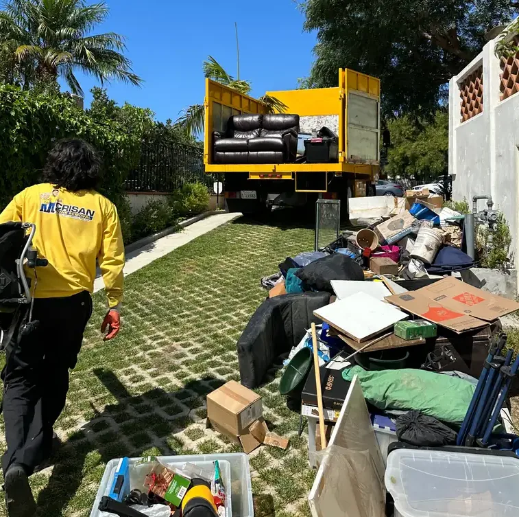 Before: a San Diego driveway piled with old furniture, boxes and household junk next to the Crisan Junk Removal truck